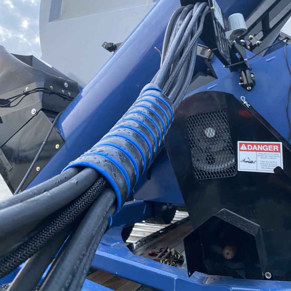 Hose tamer in blue keeping many hydraulic hoses together in a group.